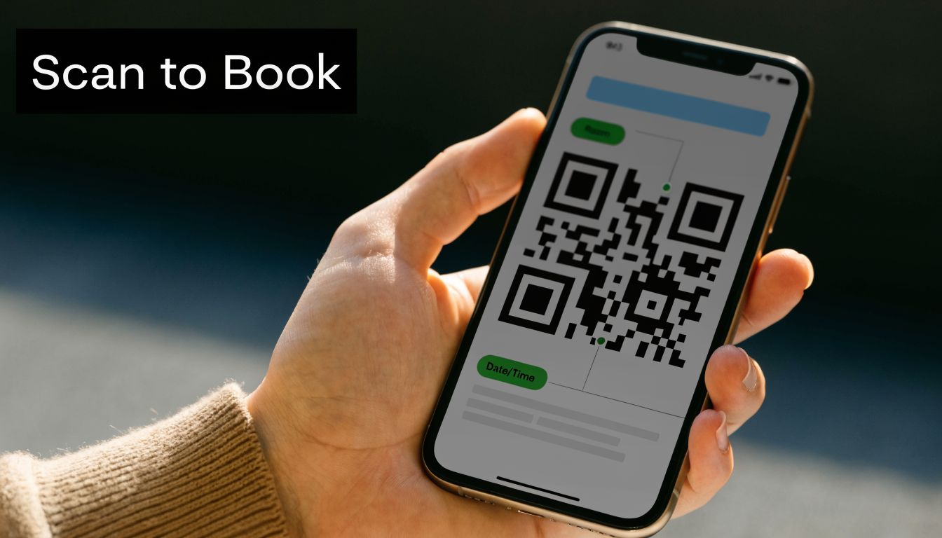 A close-up of a hand holding a smartphone displaying a QR code for room booking.