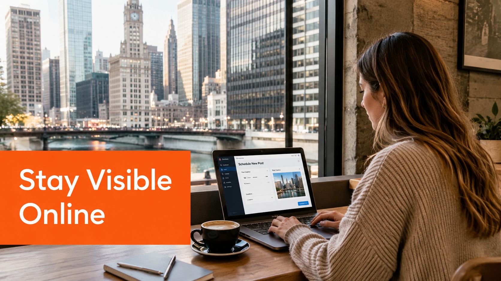 A woman working on a laptop at a cafe overlooking the Chicago skyline while scheduling social posts.